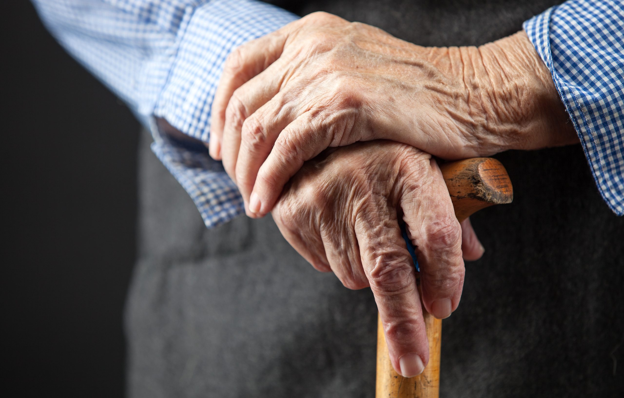 Closeup,Of,Senior,Woman's,Hands,On,Wooden,Walking,Stick